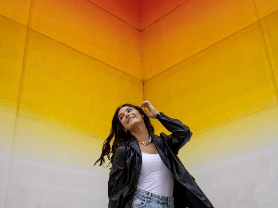 College student flipping her hair in front of the Tau Ceti artwork in downtown Austin