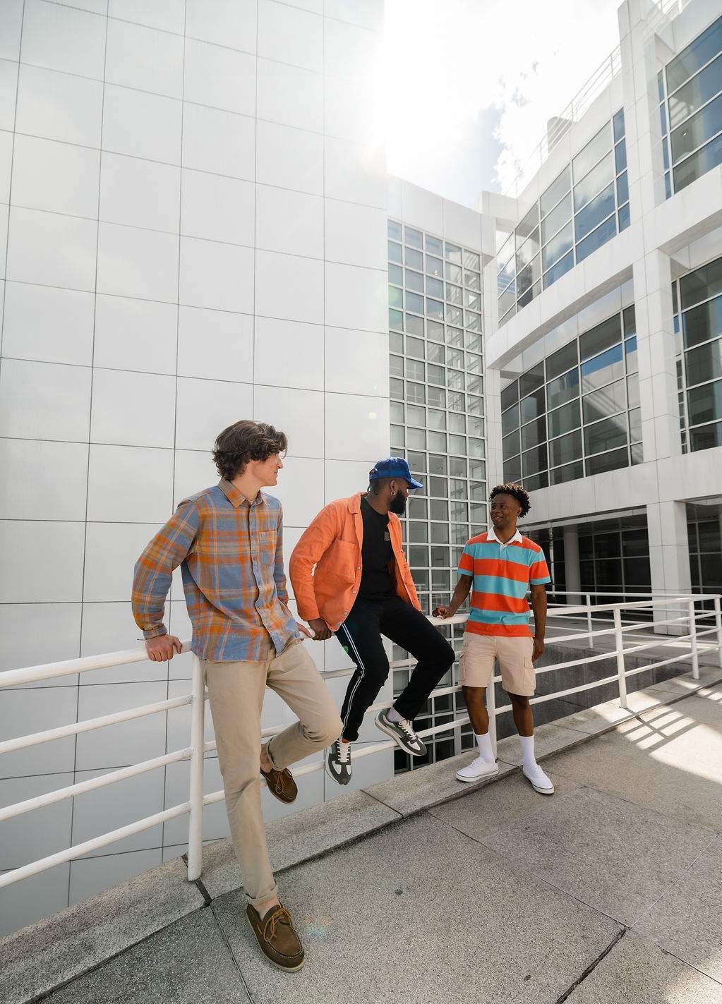 Three college friends hanging out outside of the entrance to a building