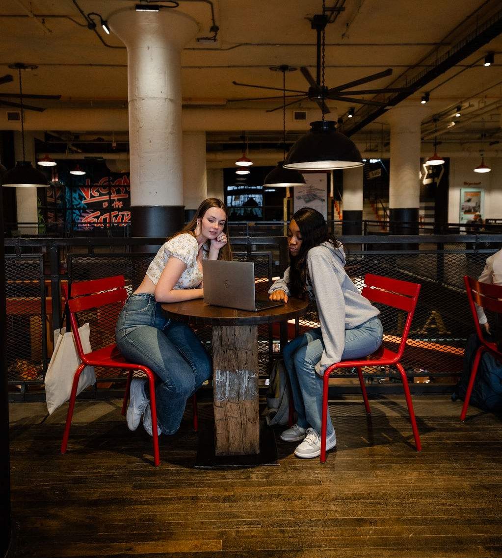 Two college students looking at a computer together in a coffee shot