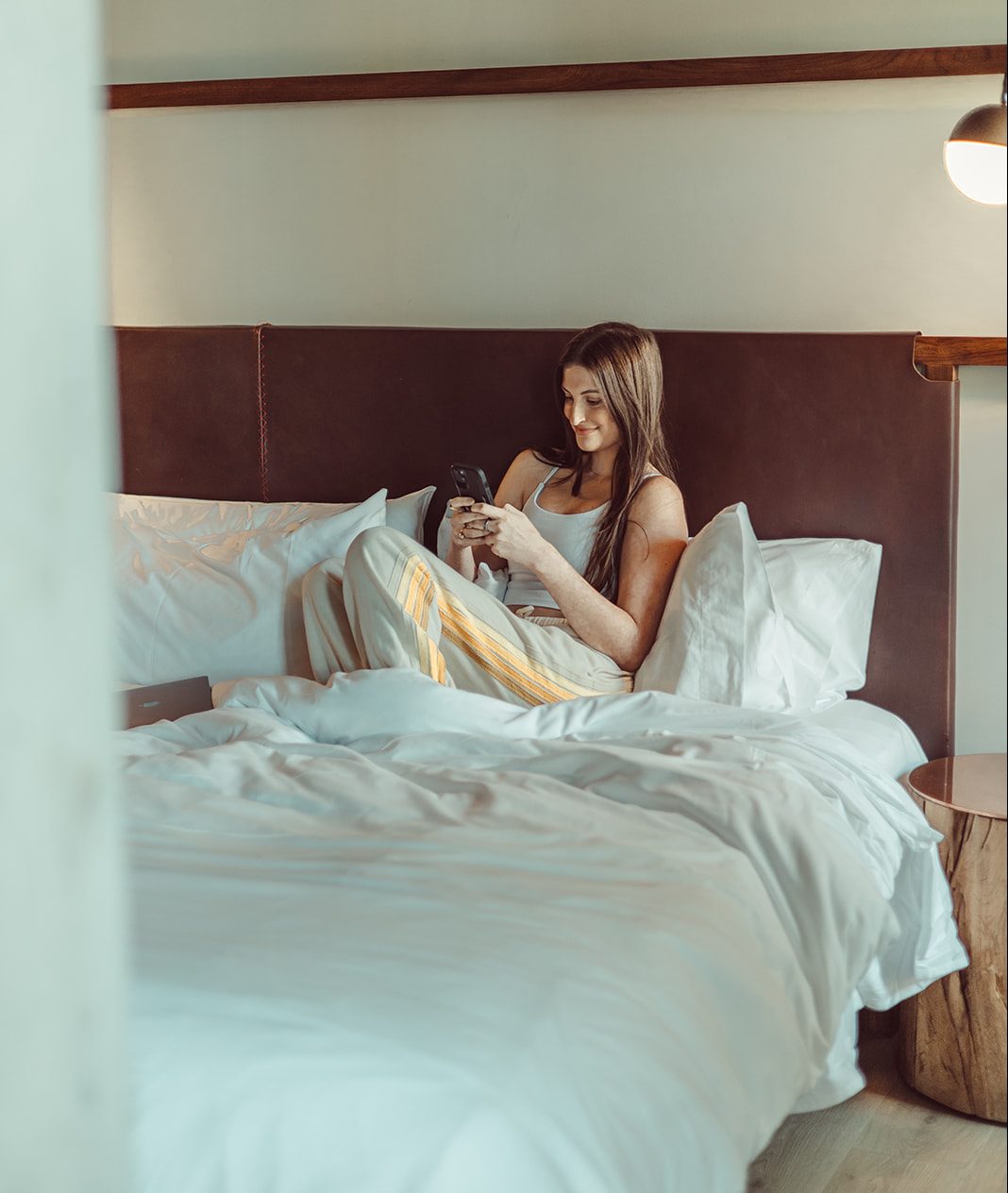 A girl smiles while texting her friends from her bed in her brand new apartment