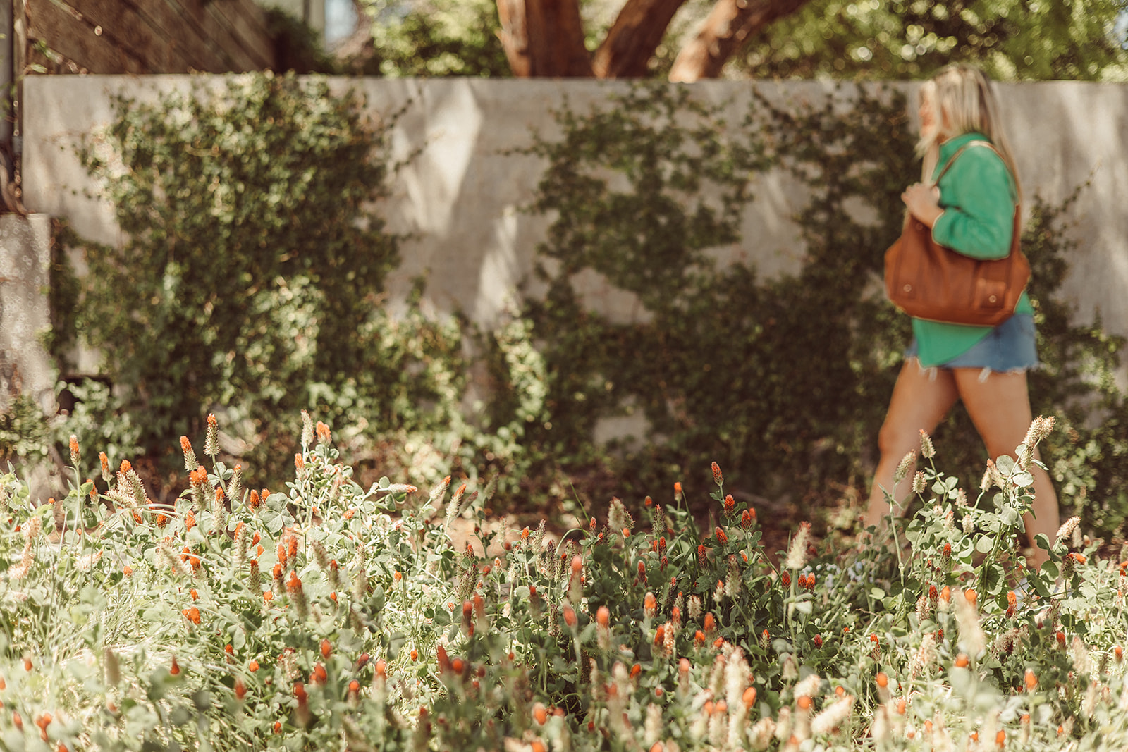 A girl walks down the sidewalk surrounded by greenery in West Campus