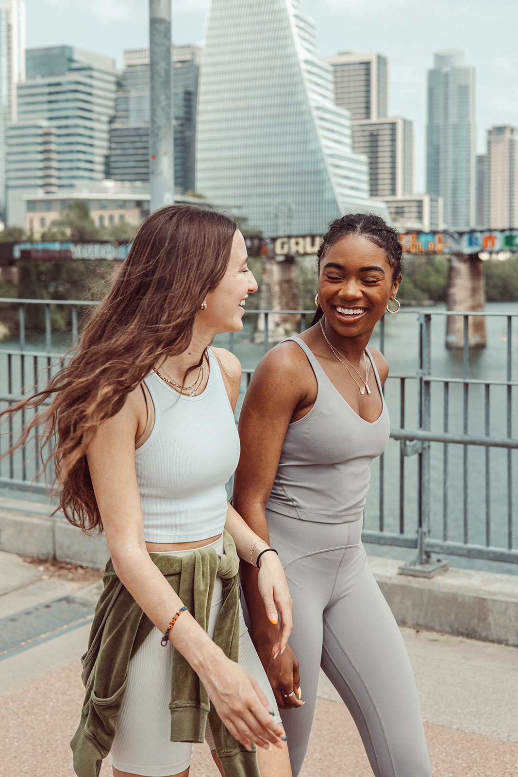 Two roommates share a laugh while strolling down the Pfluger Bridge in Austin, Texas