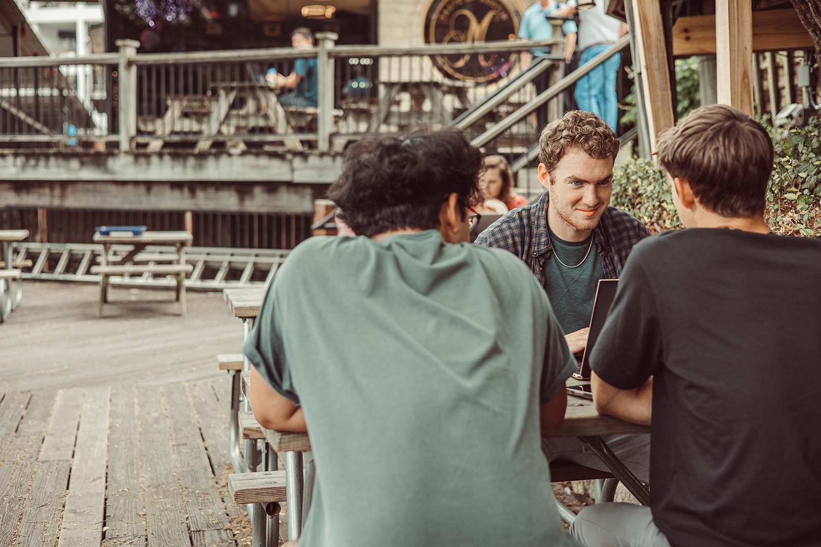 Three UT students study with at a picnic table on the deck of Mozart's Coffee Roasters in Austin.