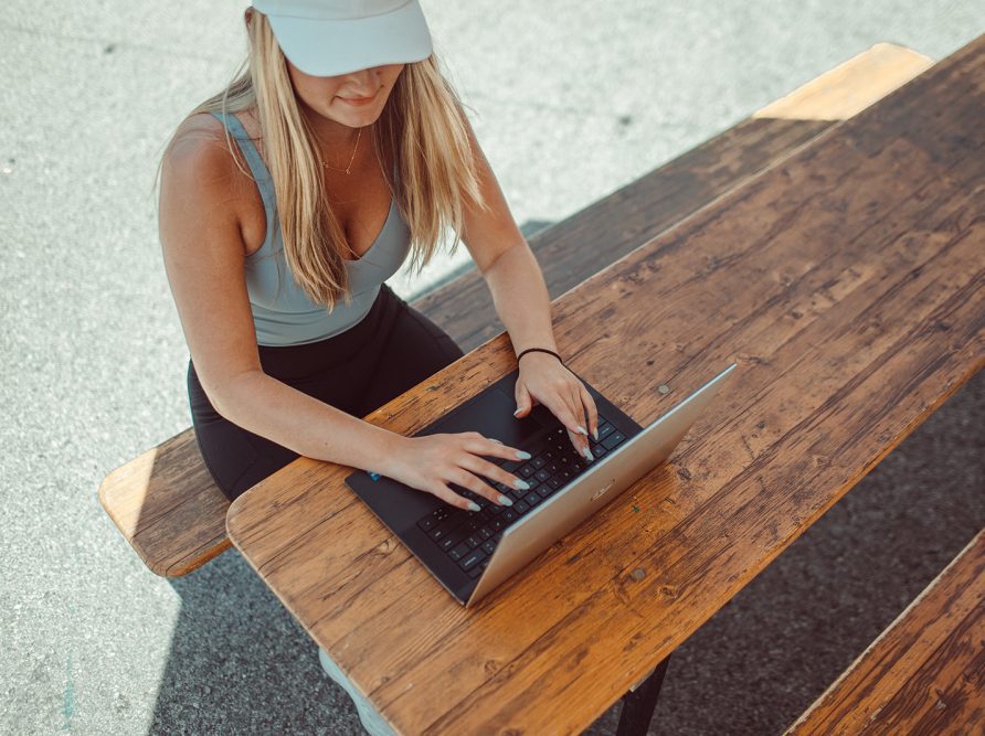 Girl working on laptop at picnic table.