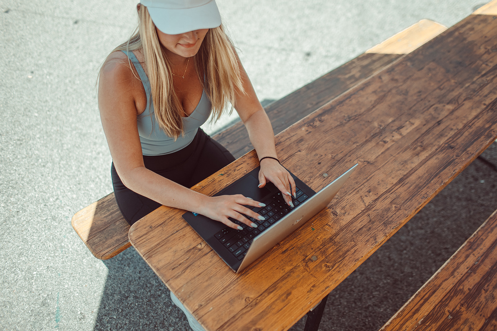 Girl working on laptop at picnic table.