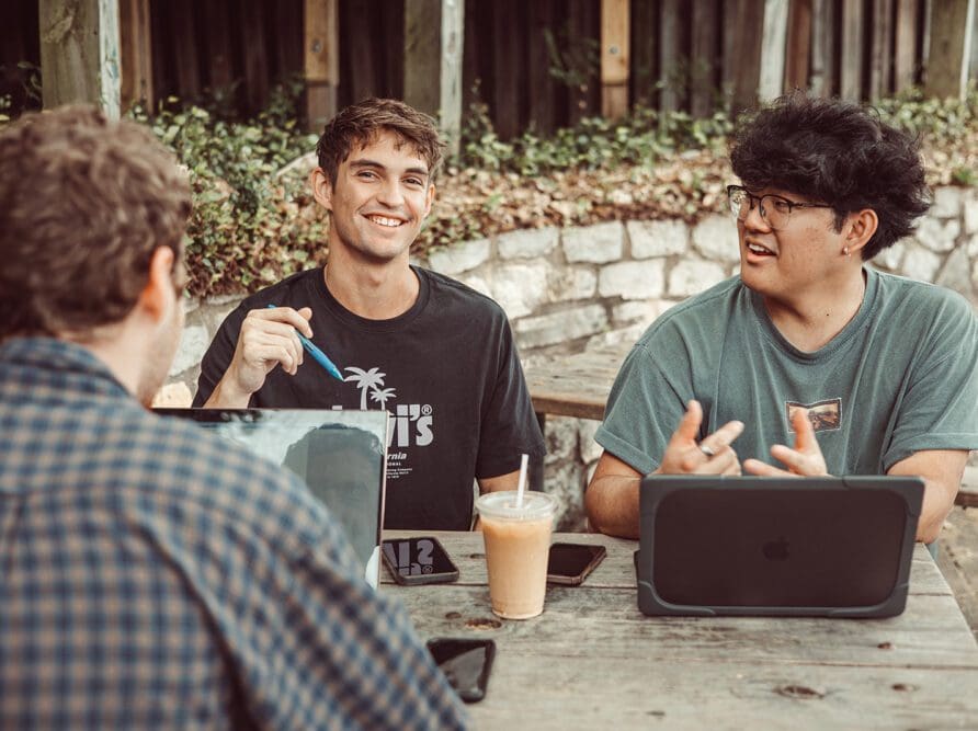 Friends laughing and talking while doing work at a coffee shop.