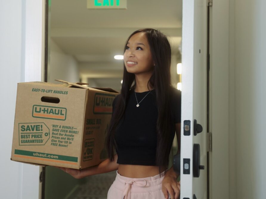Girl holding moving box walking in new apartment in West Campus Austin