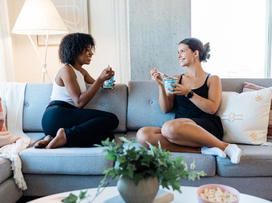 Roommates laughing and eating ice cream in their West Campus apartment