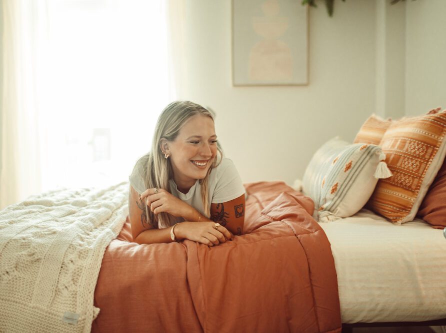 girl laying on bed in model unit bed at rambler atx