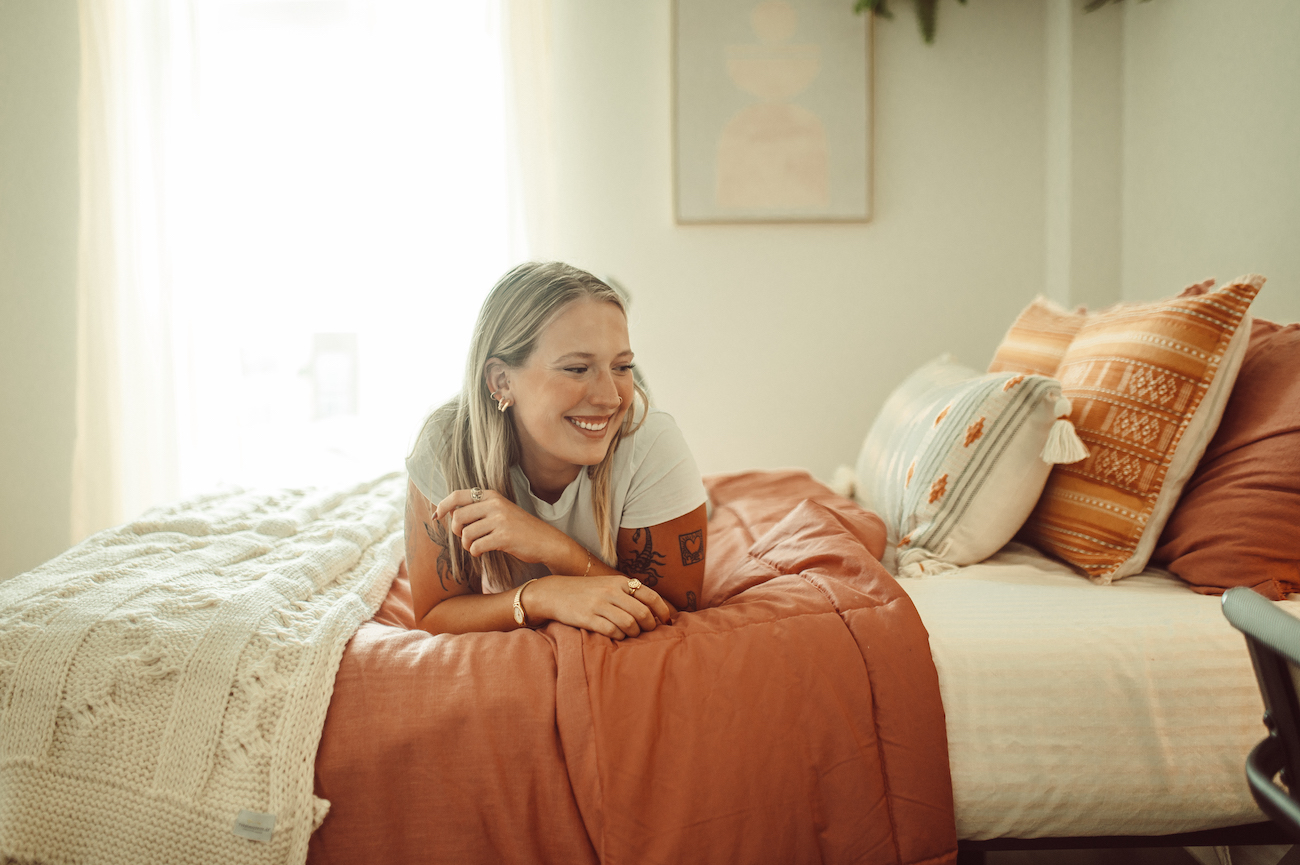 girl laying on bed in model unit bed at rambler atx