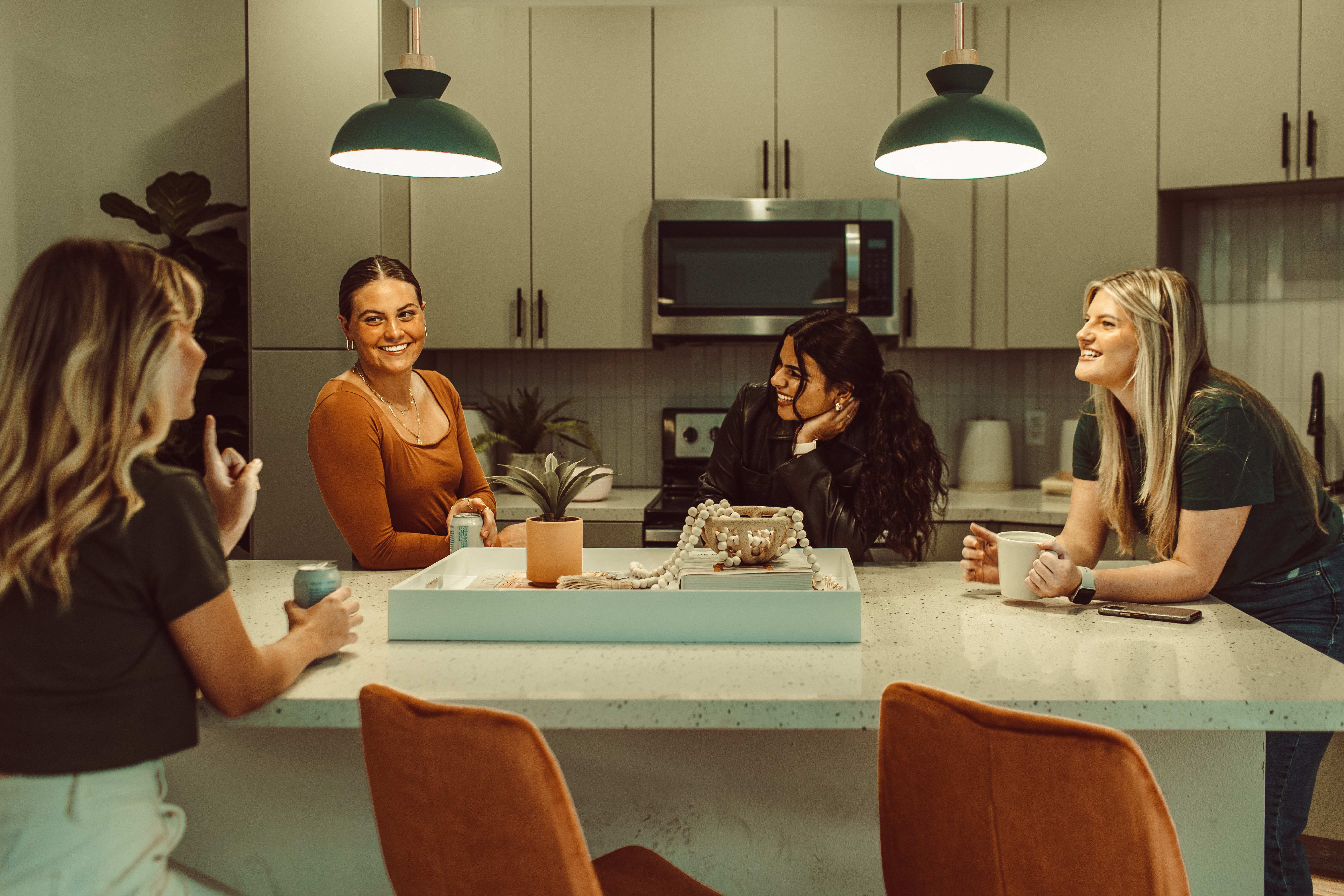 Four roommates hang out in their kitchen at Rambler, their new West Campus Austin apartment